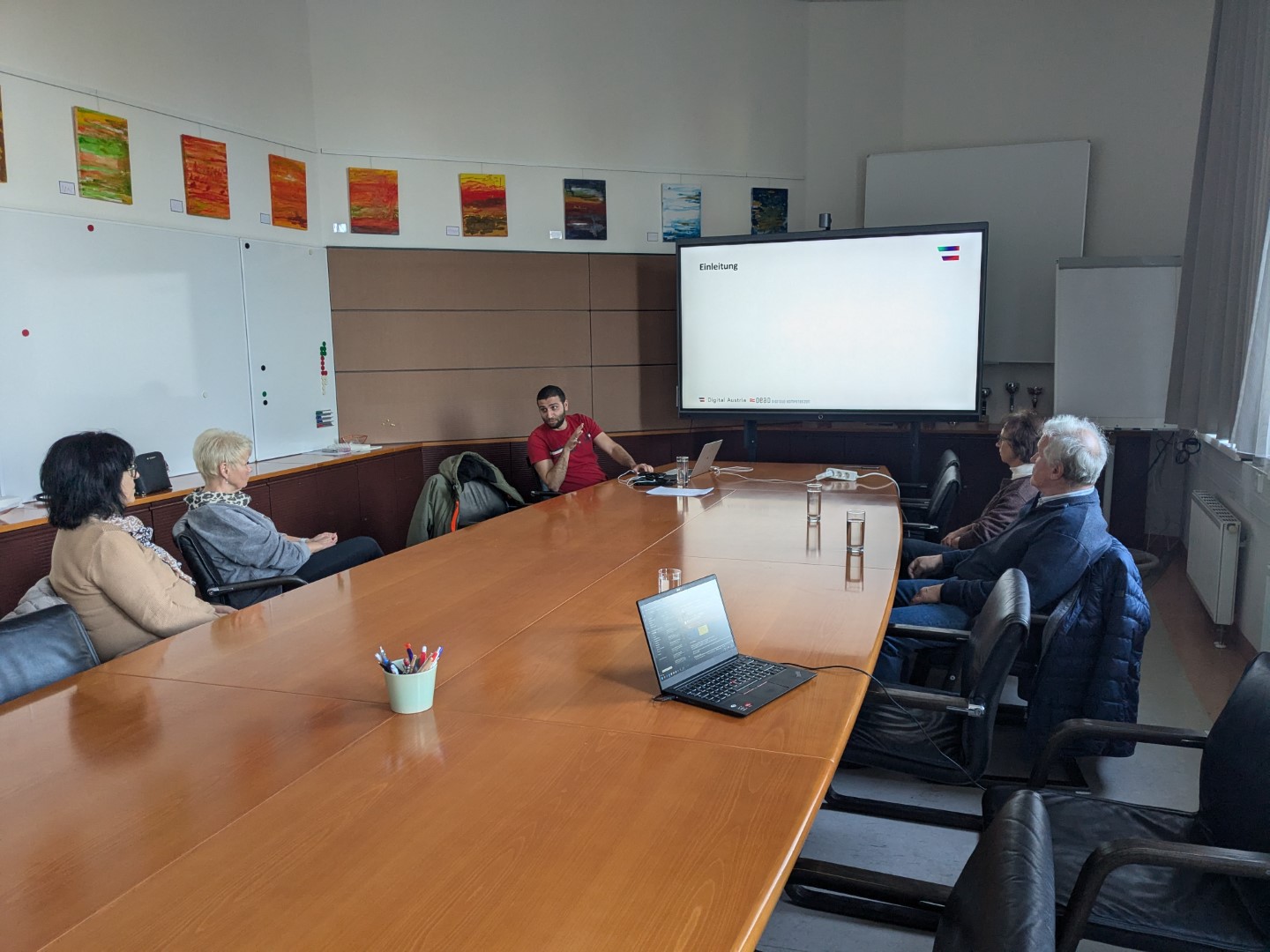 Konferenzraum mit Vortragendem und Teilnehmenden